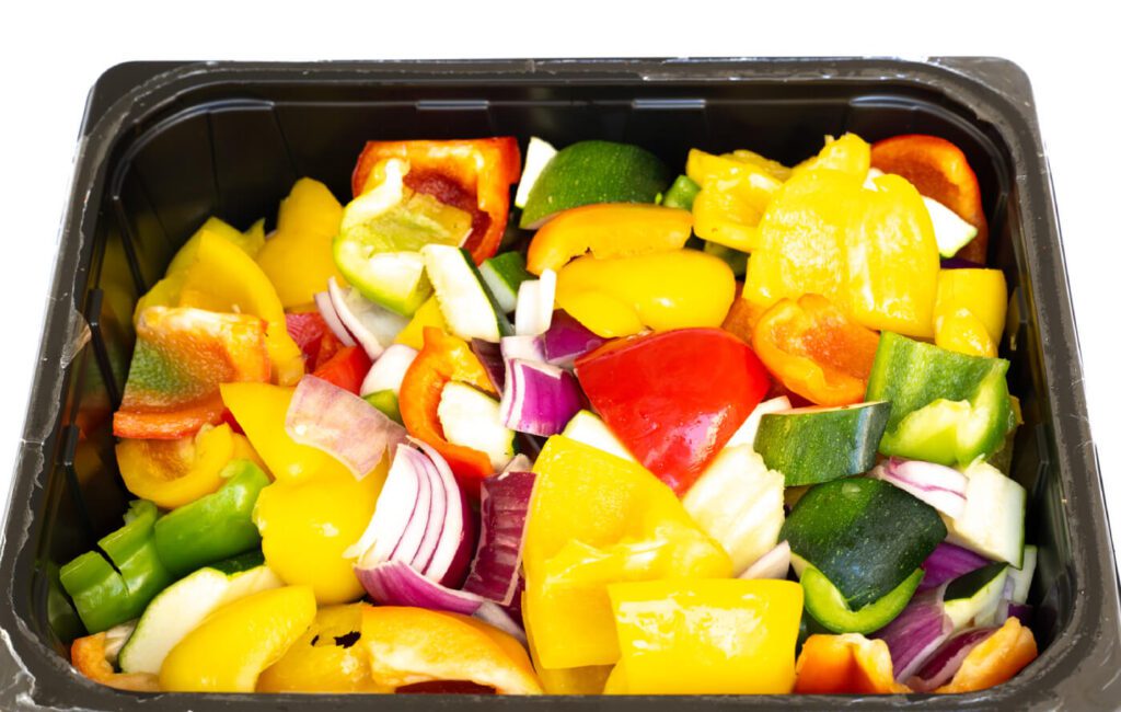 A mix of sliced vegetables including red and yellow bell peppers, red onions, and zucchini