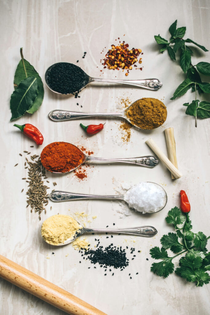 five tablespoons with a colorful array of spices and herbs