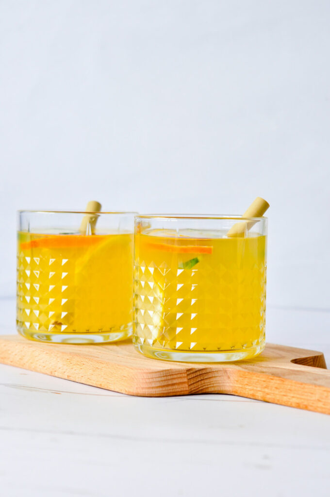 Two glasses of orange juice garnished with slices of orange and served with bamboo straws