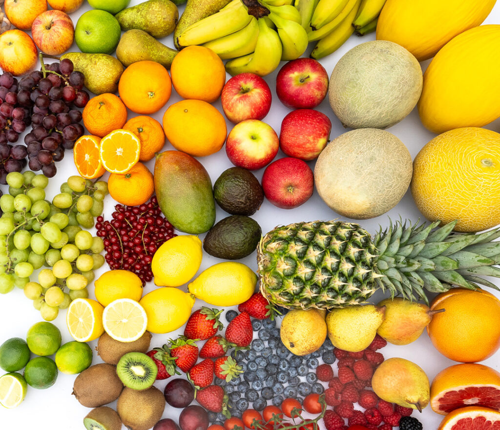 A vibrant assortment of fresh fruits, including bananas, pears, apples, oranges, melons, grapes, lemons, limes, kiwis, strawberries, blueberries, raspberries, cherries, pineapples, avocados, mangos, and more